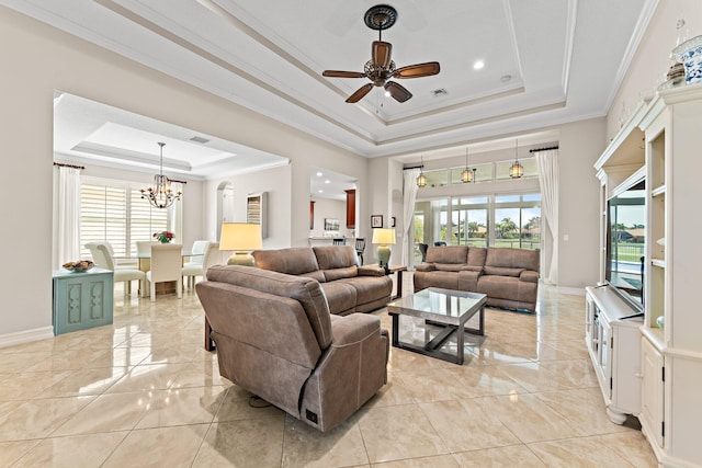 tiled living room with ceiling fan with notable chandelier, ornamental molding, a tray ceiling, and a wealth of natural light