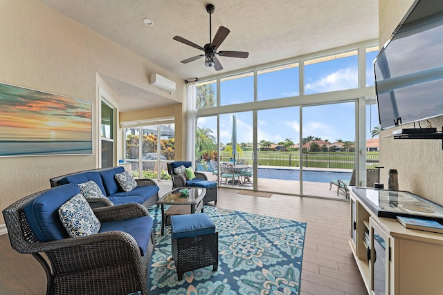 living room with ceiling fan, a textured ceiling, light hardwood / wood-style flooring, and an AC wall unit