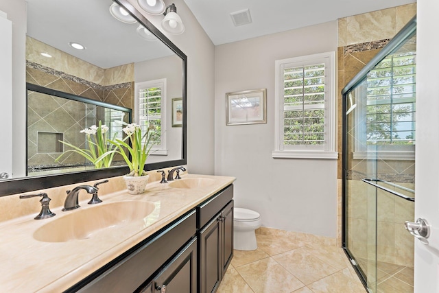 bathroom with tile patterned floors, a shower with door, vanity, and toilet