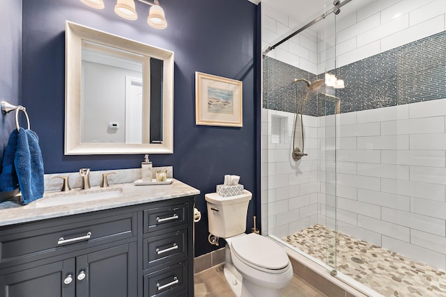 bathroom featuring tile patterned flooring, walk in shower, vanity, and toilet