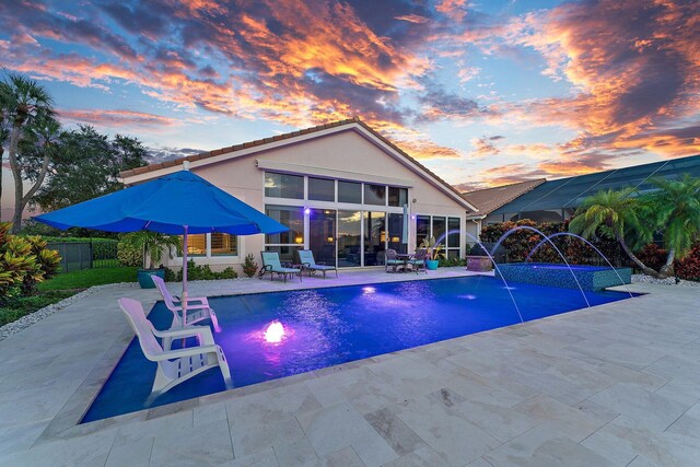 pool at dusk featuring a patio and pool water feature