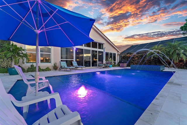 pool at dusk featuring pool water feature and a patio area