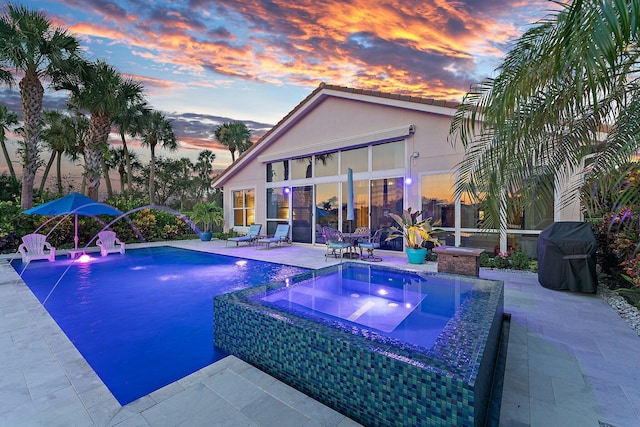 pool at dusk featuring a patio