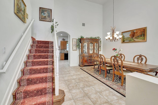 dining space featuring a notable chandelier, a towering ceiling, and light tile patterned flooring