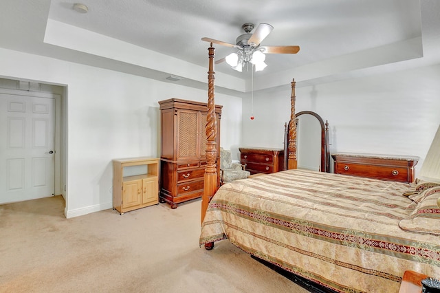 bedroom with light colored carpet, ceiling fan, and a raised ceiling