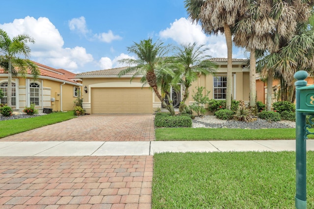 mediterranean / spanish home featuring a garage, a tiled roof, decorative driveway, a front lawn, and stucco siding