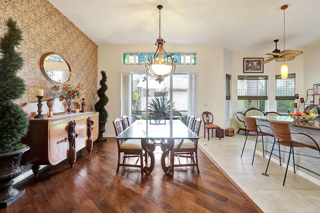 dining room with ceiling fan with notable chandelier and wood-type flooring