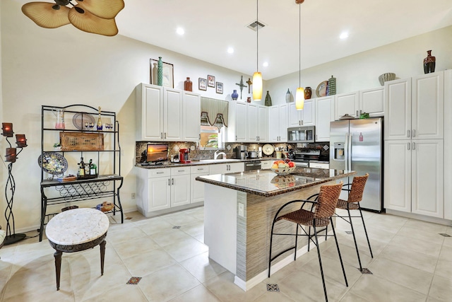 kitchen with a center island, stainless steel appliances, ceiling fan, and white cabinets