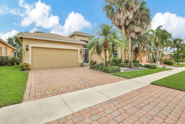 mediterranean / spanish-style home featuring stucco siding, a tile roof, an attached garage, decorative driveway, and a front yard