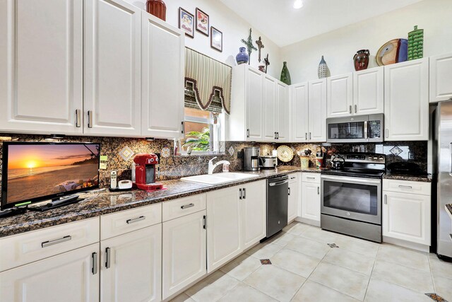 kitchen featuring white cabinets, appliances with stainless steel finishes, dark stone countertops, and sink