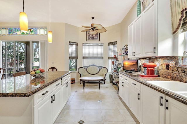 kitchen featuring ceiling fan, a kitchen island, backsplash, and white cabinets