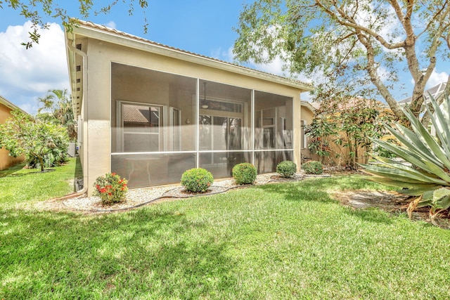 rear view of house featuring a yard and a sunroom