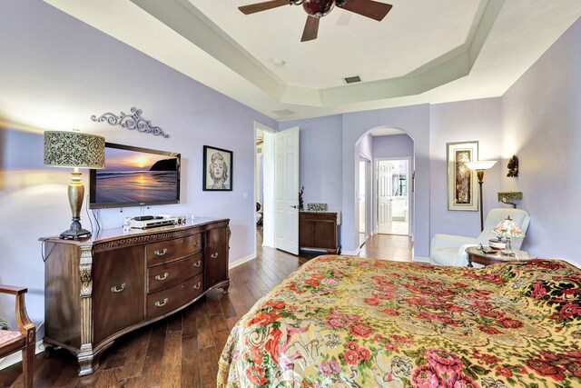 bedroom featuring a tray ceiling, wood-type flooring, and ceiling fan