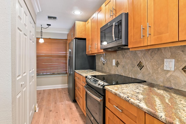 kitchen with decorative backsplash, hanging light fixtures, appliances with stainless steel finishes, light stone countertops, and light wood-type flooring