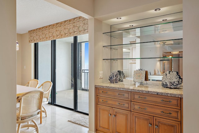 bar with a textured ceiling, light stone counters, and light tile patterned floors