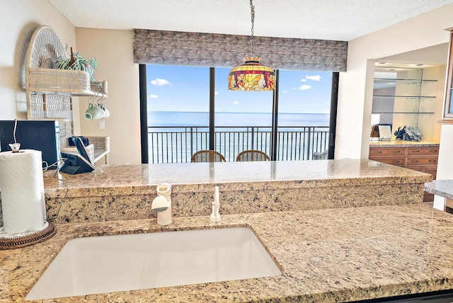 kitchen featuring a textured ceiling, decorative light fixtures, and a water view