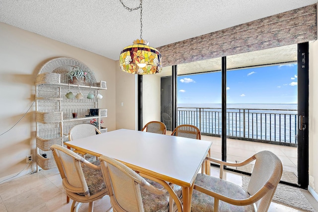 dining room with a textured ceiling, a water view, and light tile patterned floors