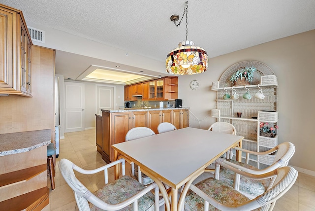 tiled dining room featuring a textured ceiling and a tray ceiling