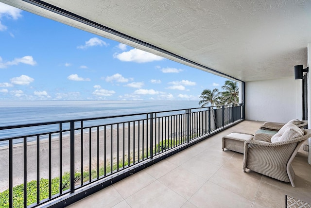 balcony with a water view and a view of the beach