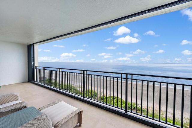 balcony featuring a view of the beach and a water view