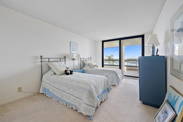 carpeted bedroom featuring access to outside, a textured ceiling, and floor to ceiling windows