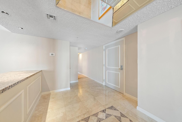 hall featuring a textured ceiling and light tile patterned floors