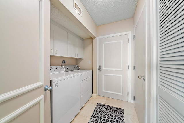 laundry room featuring washer and dryer, light tile patterned floors, a textured ceiling, and cabinets