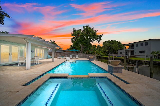 pool at dusk with a patio area