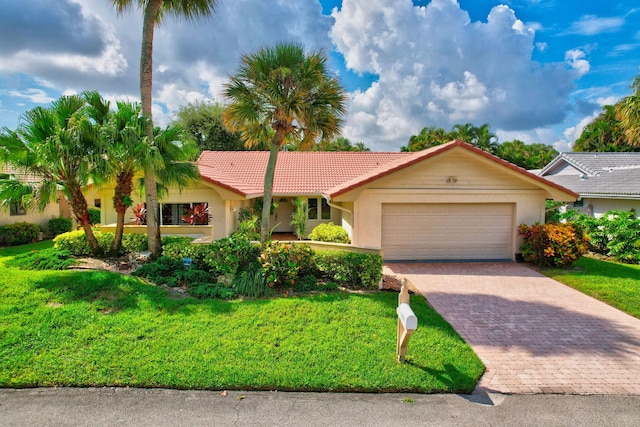 ranch-style house featuring an attached garage, a tile roof, decorative driveway, stucco siding, and a front lawn