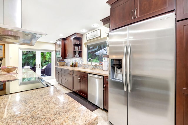 kitchen with built in appliances, range hood, light stone counters, sink, and dark brown cabinetry