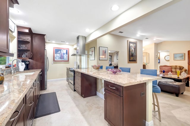 kitchen with light tile patterned floors, island range hood, stainless steel appliances, sink, and light stone counters