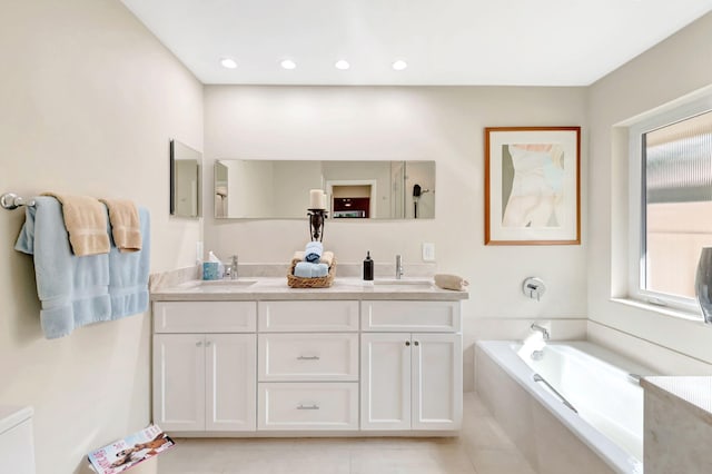 bathroom with tiled tub, vanity, and tile patterned floors