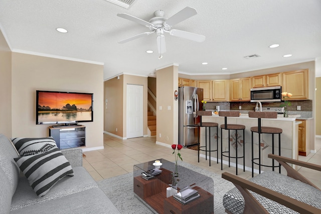 tiled living room featuring ceiling fan, a textured ceiling, and ornamental molding