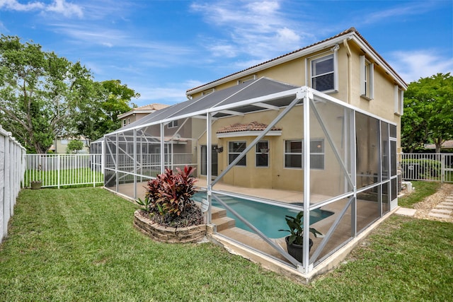 back of property with a fenced in pool, glass enclosure, and a yard