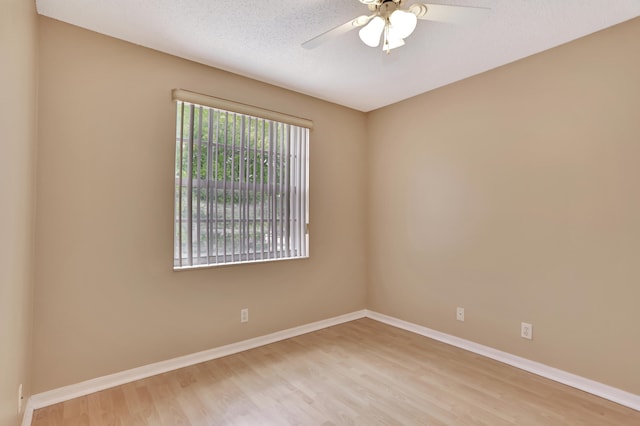 empty room with a textured ceiling, light wood-type flooring, and ceiling fan