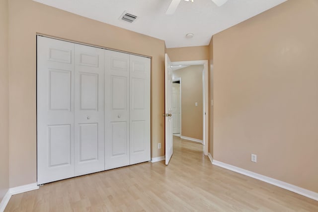 unfurnished bedroom with ceiling fan, a closet, light hardwood / wood-style floors, and a textured ceiling