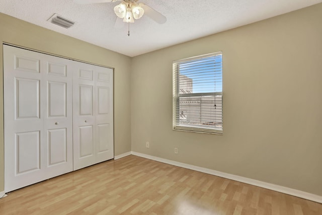 unfurnished bedroom featuring a textured ceiling, light wood-type flooring, a closet, and ceiling fan