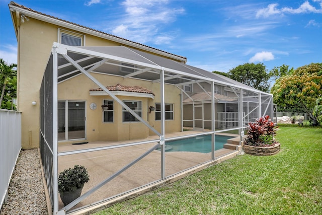 rear view of property with a patio, glass enclosure, and a lawn