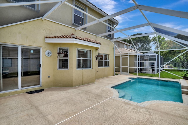 view of pool with glass enclosure and a patio area