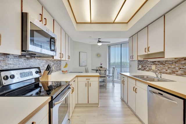 kitchen with sink, decorative backsplash, ceiling fan, and stainless steel appliances