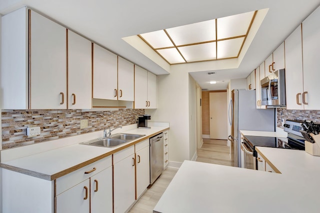 kitchen featuring appliances with stainless steel finishes, white cabinetry, sink, and tasteful backsplash