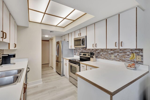 kitchen featuring sink, appliances with stainless steel finishes, light hardwood / wood-style floors, tasteful backsplash, and white cabinetry