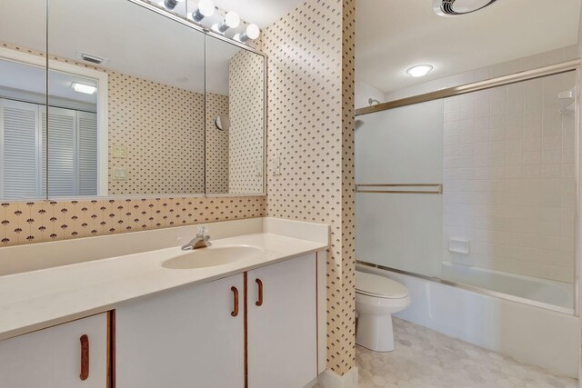 full bathroom with tile patterned floors, vanity, bath / shower combo with glass door, and toilet