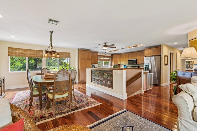 dining room featuring ceiling fan with notable chandelier, plenty of natural light, and dark hardwood / wood-style floors