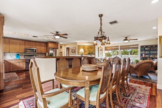 dining area featuring ceiling fan with notable chandelier and dark hardwood / wood-style floors