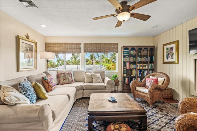 living room featuring ceiling fan, a textured ceiling, and hardwood / wood-style flooring