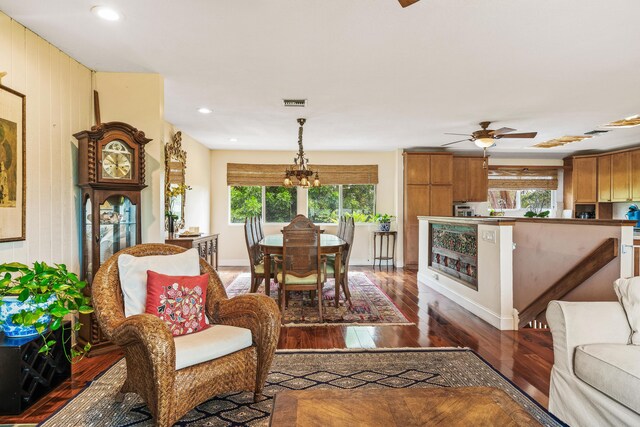 living room featuring ceiling fan with notable chandelier and wood-type flooring