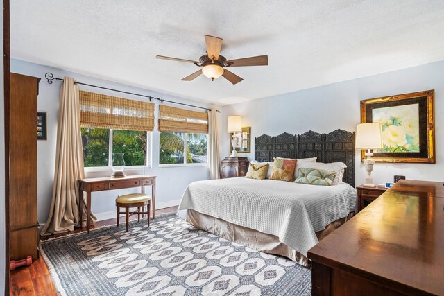 bedroom with hardwood / wood-style flooring, a textured ceiling, and ceiling fan