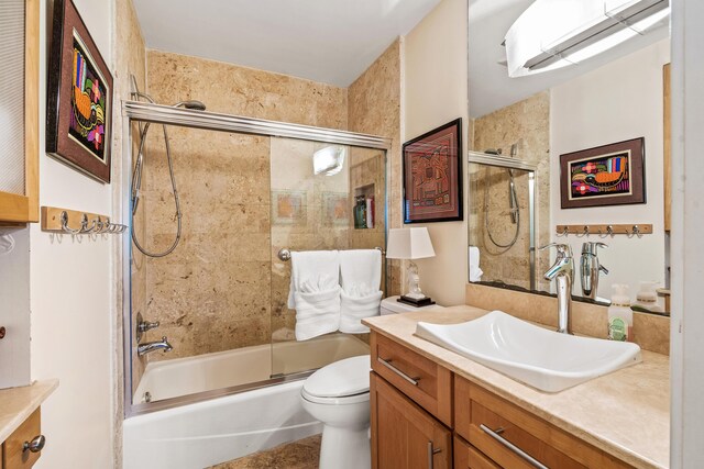 full bathroom with combined bath / shower with glass door, toilet, and vanity