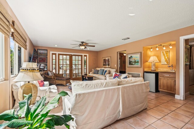 living room with ceiling fan, light tile patterned flooring, a healthy amount of sunlight, and french doors